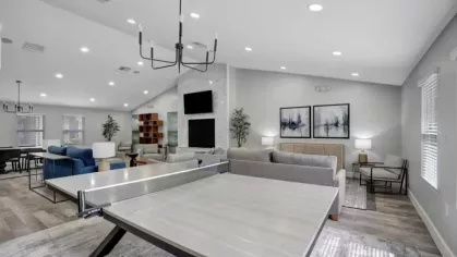 A community lounge with a ping-pong table and ample seating under high ceilings.