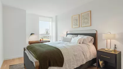 Comfortable bedroom with a cozy bed, elegant nightstand lamps, and a desk near a large window.