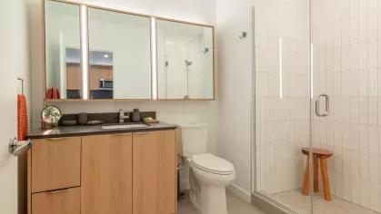 Contemporary bathroom with a glass-enclosed walk-in shower, illuminated mirrors, and a wood-accented vanity.