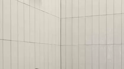 Modern shower with sleek chrome fixtures and white vertical subway tile walls.