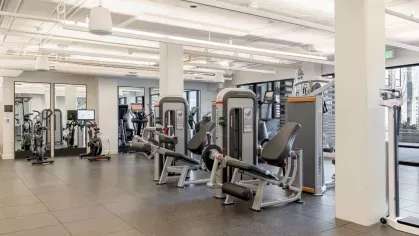 A spacious fitness center with state-of-the-art cardio machines, weight training equipment, and full-length mirrors, offering a comprehensive workout experience for residents.