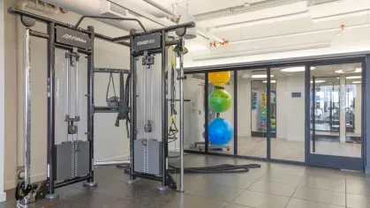 A spacious fitness center with state-of-the-art cardio machines, weight training equipment, and full-length mirrors, offering a comprehensive workout experience for residents.