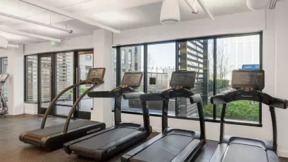 A spacious fitness center with state-of-the-art cardio machines, weight training equipment, and full-length mirrors, offering a comprehensive workout experience for residents.