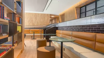 An inviting library space at The Edmund Apartments with comfortable seating, wooden floors, and floor-to-ceiling shelves filled with books for residents to enjoy.