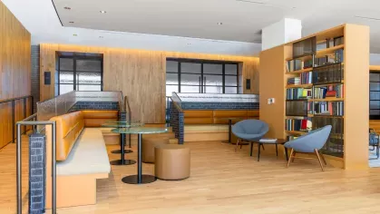 An inviting library space at The Edmund Apartments with comfortable seating, wooden floors, and floor-to-ceiling shelves filled with books for residents to enjoy.