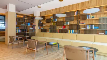 An inviting library space at The Edmund Apartments with comfortable seating, wooden floors, and floor-to-ceiling shelves filled with books for residents to enjoy.