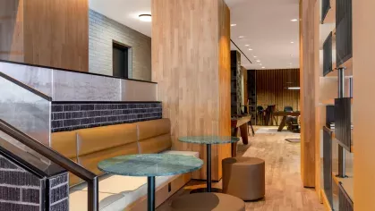  A modern lounge area at The Edmund Apartments featuring a cozy fireplace, sleek furniture, and a stylish bookshelf wall, designed for relaxation and community interaction.