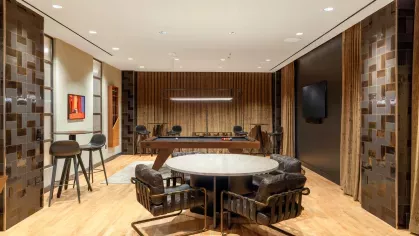 A stylish game room at The Edmund Apartments, equipped with a pool table, shuffleboard, and contemporary seating areas for entertainment and socializing.