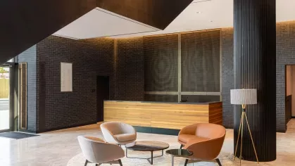 A sophisticated lobby at The Edmund Apartments showcasing a modern reception desk, artistic decor, and comfortable seating, creating a welcoming atmosphere.