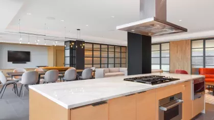 A state-of-the-art chef’s kitchen with a marble-topped island, bar stools, and high-end appliances in an open-concept design.