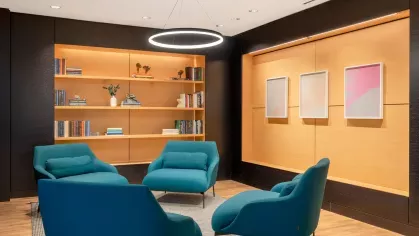 An elegant meeting space featuring a combination of blue and brown contemporary chairs, accent lighting, and a warm wooden floor.