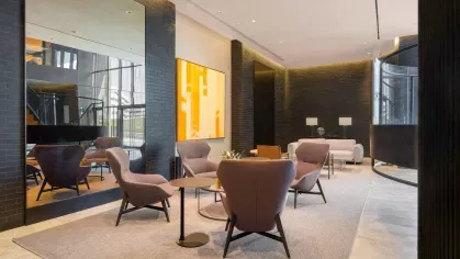 An elegant meeting space featuring a combination of blue and brown contemporary chairs, accent lighting, and a warm wooden floor.