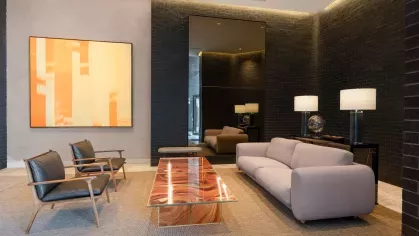 An elegant meeting space featuring a combination of blue and brown contemporary chairs, accent lighting, and a warm wooden floor.