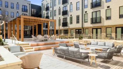 Open-air courtyard with cozy seating, wooden pergolas, and decorative string lighting at The Edmund Apartments.