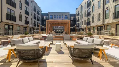 Open-air courtyard with cozy seating, wooden pergolas, and decorative string lighting at The Edmund Apartments.