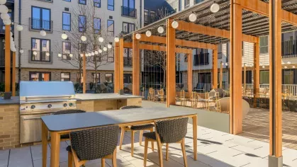 Stylish outdoor lounge with modern furniture and community grilling stations, perfect for social gatherings.