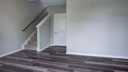 A view of the staircase in a bright and spacious room with hardwood flooring and neutral wall colors at The Grove Somerset Apartments.