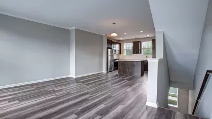 A wide-angle view of an open floor plan with a kitchen, dining, and living area, showcasing contemporary design and ample natural light.