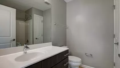 A sleek bathroom with a modern sink, dark cabinetry, and a shower area, highlighting the contemporary amenities at The Grove Somerset Apartments.