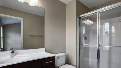 Primary bathroom with a walk-in shower, vanity, and ample lighting.