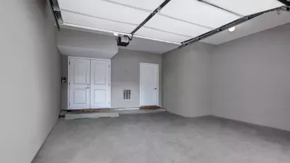 Spacious garage with concrete flooring, overhead door, and direct entry into the building.