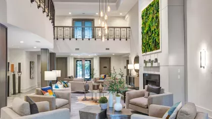 Elegant clubhouse with double-height ceilings, cozy seating arrangements, and lush indoor greenery.