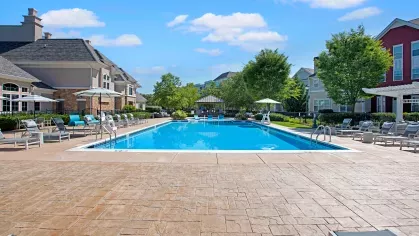 Front-facing view of the pristine swimming pool and surrounding greenery, offering a relaxing outdoor experience for residents at The Grove Somerset Apartments.