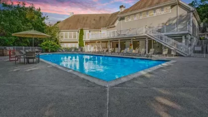 A swimming pool lit at dusk, with a warm and inviting atmosphere and colorful sky in the background.