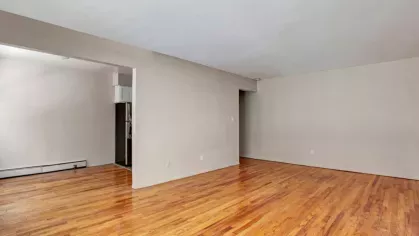 Spacious living room with polished wood floors and large windows, offering a clean and inviting atmosphere.