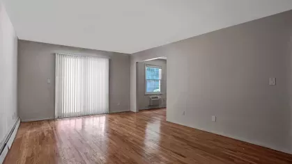 Spacious living room with polished wood floors and large windows, offering a clean and inviting atmosphere.