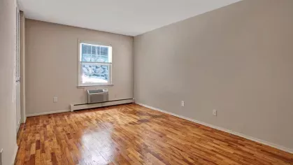 Bright bedroom with hardwood flooring, a large window for natural light, and ample closet space, ideal for restful nights.