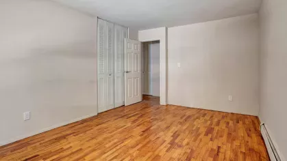 Second bedroom with a similar layout, featuring hardwood floors, a neutral color palette, and a large window.