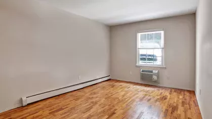 Second bedroom with a similar layout, featuring hardwood floors, a neutral color palette, and a large window.