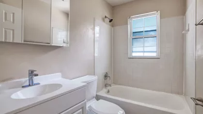 Updated bathroom featuring a clean design with a modern sink, mirror, and a bright window at The Manors Apartments.