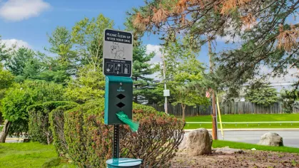 Exterior view of The Manors Apartments showcasing well-maintained green spaces, modern balconies, and a tree-lined backdrop.