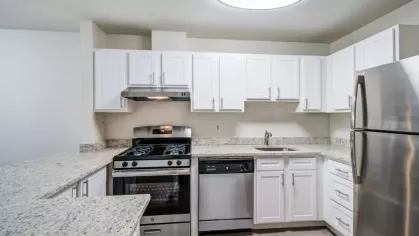 A modern kitchen featuring white cabinets, granite countertops, and stainless steel appliances.