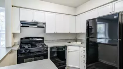 A compact kitchen with black appliances, white cabinets, and ample counter space.