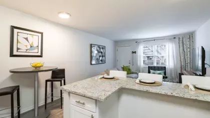 A cozy dining nook with a round table and a modern kitchen in the background.