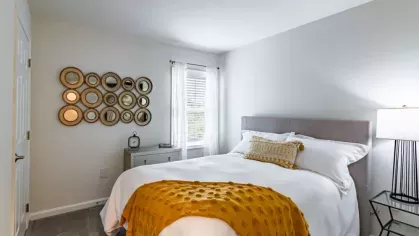 A cheerful bedroom with a sunny yellow blanket and decorative circular mirrors.