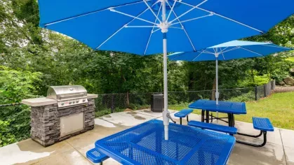 A patio area with blue umbrella-shaded tables and a built-in grill.
