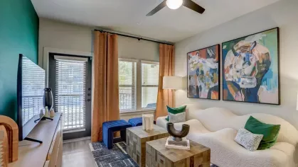 A stylish living area featuring abstract artwork, cozy seating, and natural light from large windows in a Tropia Wellen Park apartment.