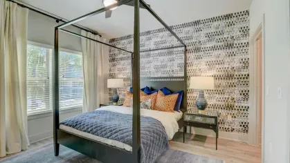 A bedroom with a four-poster bed, patterned accent pillows, and an artistic feature wall, blending comfort and style.