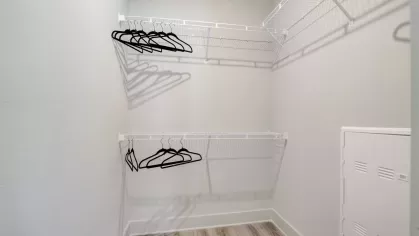 A walk-in closet with wire shelving and several black hangers neatly arranged, showcasing ample storage space.