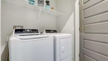 Image 8: In-unit laundry area featuring a washer, dryer, and storage shelf, perfect for modern convenience.