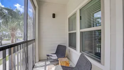 Image 9: Private screened balcony with comfortable seating, offering scenic views of palm trees and a serene atmosphere.