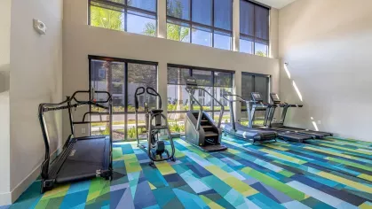 Image 1: Fitness center with modern exercise equipment, including a functional trainer, punching bag, and kettlebells, overlooking landscaped views through large windows.