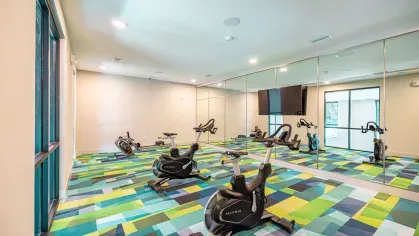 Image 1: Fitness center with modern exercise equipment, including a functional trainer, punching bag, and kettlebells, overlooking landscaped views through large windows.