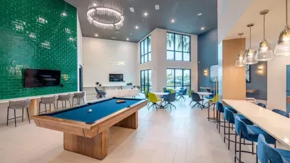 Image 6: Luxurious game room with a billiards table, cozy seating areas, and contemporary lighting at Tropia Wellen Park Apartments.