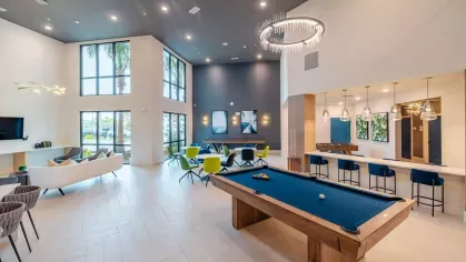 Image 6: Luxurious game room with a billiards table, cozy seating areas, and contemporary lighting at Tropia Wellen Park Apartments.