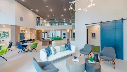 Image 2: Open-concept clubhouse with vibrant seating, a pool table, and a chandelier, perfect for relaxation or socializing at Tropia Wellen Park Apartments.
